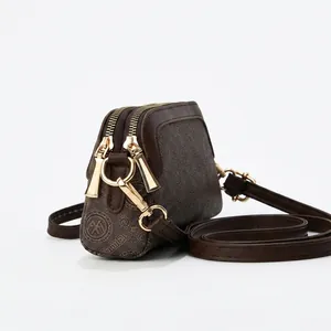 Detail view of mini brown crossbody bag with retro print and golden double zippers