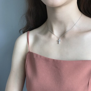 Close-up of 925 sterling silver cross pendant with pavé diamonds on a thin chain