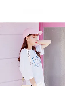 Model wearing pale pink baseball cap with beige canvas crossbody bag in trendy style