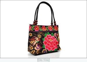 Detailed side view of ethnic canvas bag with floral embroidery and polished wood beads