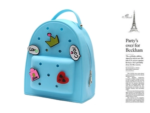 Close-up of sky blue silicone backpack with colorful cartoon charms and DIY holes