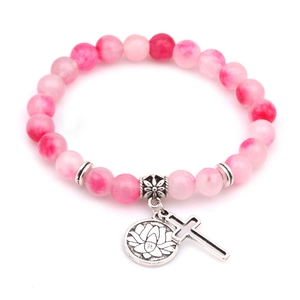 Dettaglio del bracciale con perline rosa e ciondoli a forma di loto e croce d'argento