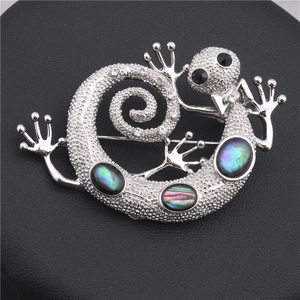 Macro shot of silver gecko brooch with colorful abalone shell and white rhinestones