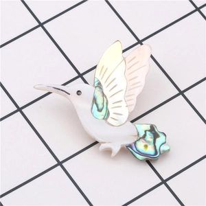 Macro view of handmade hummingbird brooch with iridescent wings on grid background