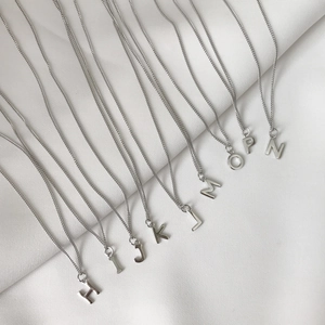Detailed view of sterling silver necklaces featuring multiple alphabet letter pendants