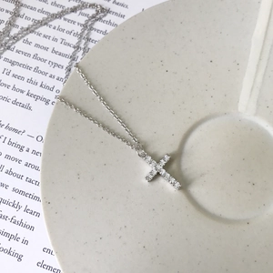 Detailed view of a silver sparkling cross pendant with zircons on a textured plate