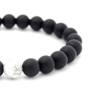 Macro detail of 8mm matte black beads and a white turquoise stone on a beaded bracelet