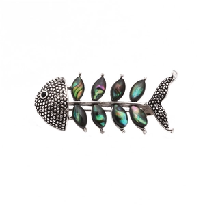Macro detail of retro silver fish bone brooch with iridescent abalone shell inlay