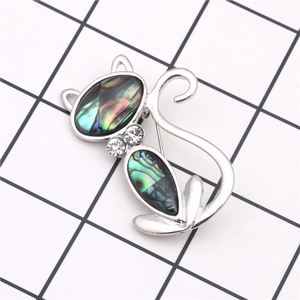 Detailed view of cat brooch featuring iridescent shell body and silver metal tail accents