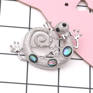 Detailed view of silver gecko brooch with abalone shell inlays and sparkling rhinestones