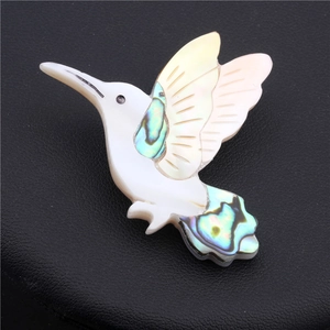 Detailed view of hummingbird brooch with abalone shell inlay on black display stand