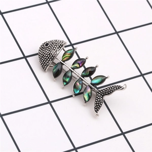 Detailed close-up of fishbone brooch featuring iridescent abalone shell and silver alloy