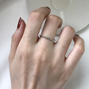 Detailed close-up of a twisted rope S925 sterling silver ring worn on a model hand