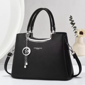 Close-up of black lychee grain leather handbag with silver hardware and pearl pendant