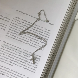 Detailed view of S925 silver cross pendant with pavé crystals on a minimalist book