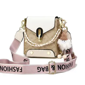 Close-up of elegant crossbody bag with monogram pattern, metal lock and fuzzy bag charm