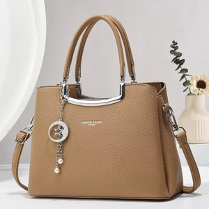 Close-up of brown pebbled leather texture on structured handbag with silver U-shaped metal trim