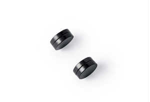 Macro detail of pair of black magnetic stud earrings with smooth round metal surface