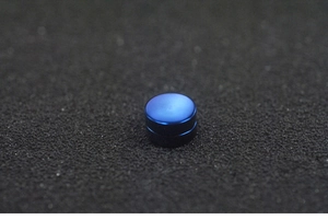 Macro shot of blue matte magnetic stud earring for men on black textured background