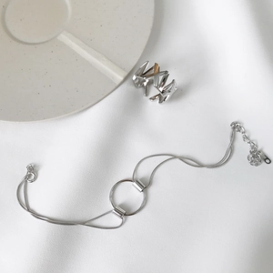 Macro shot of S925 sterling silver geometric chain bracelet and matching ring on fabric