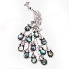 Macro shot of silver peacock brooch with abalone shell inlay and sparkling crystals