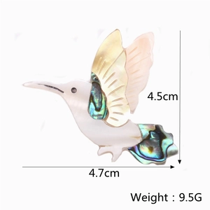 Macro shot of hummingbird brooch with white mother of pearl and green abalone shell inlay