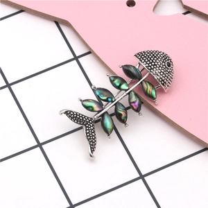 Macro shot of silver fishbone brooch with iridescent abalone shell inlay details