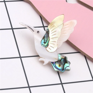 Detail of hummingbird brooch with colorful abalone shell texture on wings and tail