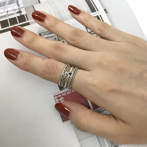 Close-up of stacked S925 silver rings with crown and geometric designs on model hand
