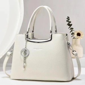 Detail of white lychee leather handbag featuring silver hardware and a star charm