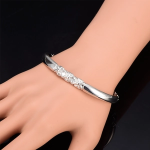 Detail of silver alloy bracelet featuring intricate 3D floral carvings and relief patterns
