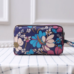 Detailed view of navy floral canvas purse with three layers of zippers and wrist strap