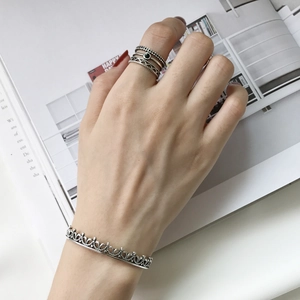 Detail of vintage 925 sterling silver stacked rings and crown cuff bracelet on model