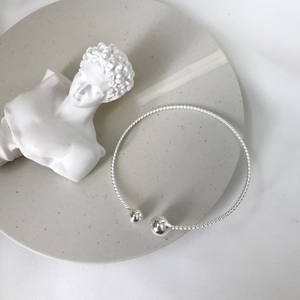 Dettaglio ravvicinato del bracciale rigido aperto in argento S925 con design a corda