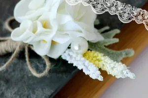 Close-up of white calla lily and rose boutonniere with pearl and burlap twine detail