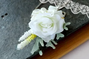 Detailed view of handmade white calla lily and rose boutonniere for wedding suit lapel