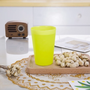 Detailed close-up of a vibrant yellow plastic stacking cup on a wooden tray surface