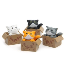 Detailed close-up of four cute resin cat figurines in cardboard boxes for desk decor
