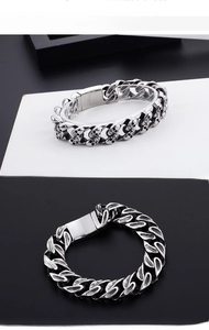Macro view of men's stainless steel heavy curb chain bracelet with skull relief details