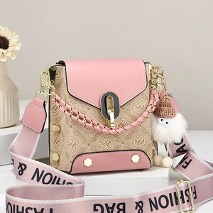 Pink and beige crossbody bag with wide logo strap and plush doll charm on white steps