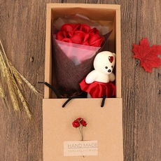 Detail view of handmade gift box with red roses and white teddy bear on wood table