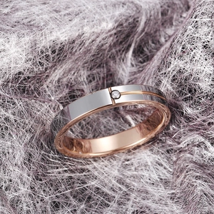 Polished silver and rose gold tungsten ring with a single zircon on purple fiber