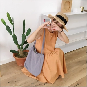 Close-up of bright orange linen sleeveless dress and minimalist grey canvas tote bag