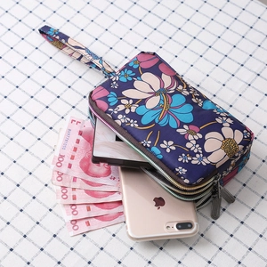 Three-layer canvas wristlet purse with floral pattern holding phone and cash