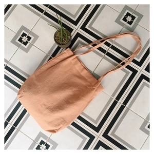 Overhead shot of minimalist apricot linen tote bag on geometric tile background