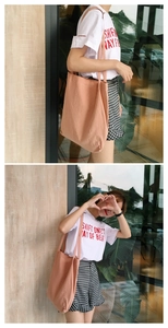 Detail of a peach-pink washed cotton canvas tote bag carried by a model in casual style