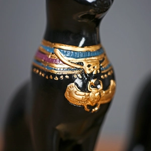 Detail van Egyptisch Bastet kattenbeeld met gouden scarabee hanger en kleurrijke kraag