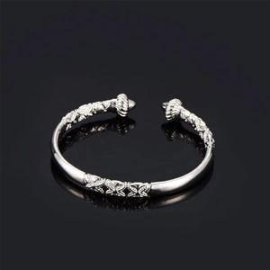 Detail of silver-colored open bangle with embossed floral patterns and rope twist ends