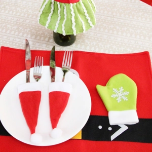 Close-up of festive Christmas hat cutlery holders and Santa style placemats on dining table