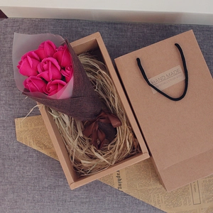 Macro view of 7 deep pink soap roses in a burlap wrap inside a kraft gift box